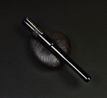 Load image into Gallery viewer, A Franklin-Christoph Model 02 Intrinsic Black Knight fountain pen lies diagonally on textured dark stone, black background.