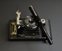 Load image into Gallery viewer, A black Kodak camera with a Franklin-Christoph Model 02 Intrinsic pen (#6 nib) lies diagonally across it.