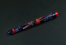 Load image into Gallery viewer, A Franklin-Christoph 03 A.A. Vacharat pen with neon art and red ends rests on a dark surface.