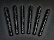 Load image into Gallery viewer, Seven black patterned pens, including a Franklin-Christoph 03M Artisan Delrin – Diamond Abstract, on a dark surface.