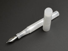 Load image into Gallery viewer, A Franklin-Christoph Model 03 Ghost fountain pen, acrylic and uncapped, rests on a dark gray surface.
