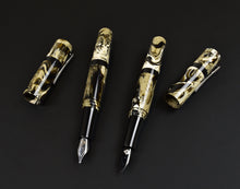 Load image into Gallery viewer, Two Franklin-Christoph Model 19 Cold Brew SE pens with #6 nibs, gold and cream marbling rest on a black surface.