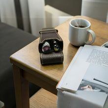 Load image into Gallery viewer, A Franklin-Christoph Two Pen Case - Napa Brown, mug, and magazine sit on a wooden table by a cozy sofa.