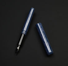 Load image into Gallery viewer, A Franklin-Christoph Model 40 Panther Modified Indigo Black SE fountain pen, uncapped, rests on a black surface.