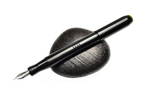 Load image into Gallery viewer, The Franklin-Christoph Model 45 Cor - Black Cathedral Fountain Pen sits diagonally on a dark stone, white background.