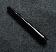 Load image into Gallery viewer, The Franklin-Christoph Model 46 Cor FP Black Cathedral rests diagonally on textured dark gray fabric, evoking fine art.