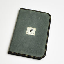 Load image into Gallery viewer, Crafted from flat, rectangular, olive-green waxed canvas, the Franklin-Christoph 5.3 Pocket Notebook Cover features rounded corners and reinforced black edge stitching for durability. Centered on the front is a small white fabric patch displaying the black Franklin-Christoph logo. This stylish notebook cover is ideal for carrying your pocket notebook or keeping fountain pen friendly paper securely protected.
