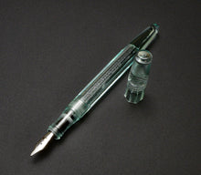 Load image into Gallery viewer, Franklin-Christoph Model 66 Septagonal Fountain Pen in Antique Glass rests on a dark surface, its silver nib gleaming.