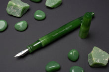 Load image into Gallery viewer, Franklin-Christoph Model 66 Septagonal Fountain Pen - Jade, silver nib, amid green stones on a dark textured surface.