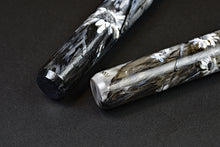 Load image into Gallery viewer, Two Franklin-Christoph 03M A.A. Vacharat Flowers on Black pens rest on a black base atop a dark, textured surface.