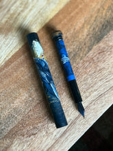 Load image into Gallery viewer, A Franklin-Christoph 33 A.A. Vacharat Moby Whale pen with ocean art rests open on a wooden surface.