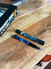 Load image into Gallery viewer, A Franklin-Christoph 33 A.A. Vacharat Moby Whale pen sits by Moby-Dick in Pictures, evoking whale and ocean art.