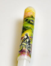 Load image into Gallery viewer, A penguin rides a bicycle on the 40 M - A.A. Vacharat by Franklin-Christoph, set in a vibrant, pen-detailed scene.