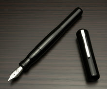 Load image into Gallery viewer, Franklin-Christoph Model 02 Intrinsic Solid Black fountain pen with #6 silver nib, hard acrylic, on a dark wooden surface.