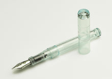 Load image into Gallery viewer, A clear Franklin-Christoph Model 03 Modified Fountain Pen - Antique Glass SE rests on a white surface, nib shown.