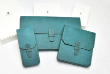 Load image into Gallery viewer, Three Franklin-Christoph Penvelope 12 cases in teal Italian leather with buckles, shown boxed on a white surface.