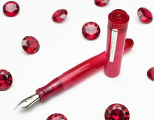 Load image into Gallery viewer, A Franklin-Christoph Model 02 Intrinsic Ruby lies amid red gemstones on a white background.