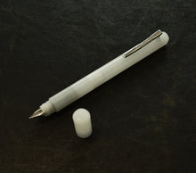Load image into Gallery viewer, A Franklin-Christoph Model 25 Eclipse Fountain Pen - Ghost, uncapped, rests on a dark textured surface.
