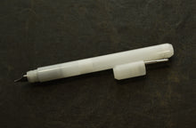 Load image into Gallery viewer, A Franklin-Christoph Model 25 Eclipse Fountain Pen - Ghost, uncapped, rests on a dark textured surface.
