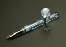 Load image into Gallery viewer, A Franklin-Christoph Model 31 Omnis - Arctic Ice SE with a silver nib rests on a dark surface.