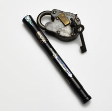 Load image into Gallery viewer, A Franklin-Christoph Model 50 Outer Banks LE pen lies near an old padlock and key, coastal relics in black abalone.
