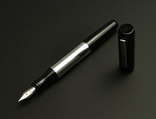 Load image into Gallery viewer, A Franklin-Christoph Model 55 Pentium FP - Black &amp; Aluminum fountain pen, cap off, sits on a dark surface.