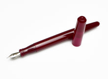 Load image into Gallery viewer, A Franklin-Christoph Model 65 Stabilis Fountain Pen in Sweet Maroon, uncapped, rests on a white surface.