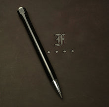 Load image into Gallery viewer, A Model 90 Artium Pencil - Black &amp; Creme’ by Franklin-Christoph rests on brown leather debossed with the F and diamonds logo.