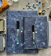 Load image into Gallery viewer, Two Franklin-Christoph NWF Snap Notebook Covers in blue with pens, styled among vintage objects and buttons on a table.