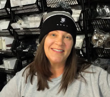 Load image into Gallery viewer, Smiling woman with long brown hair wears the Franklin-Christoph F-C Beanie in front of black storage shelves.