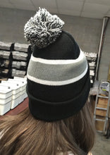 Load image into Gallery viewer, Person with long brown hair wears a Franklin-Christoph F-C Beanie (black/grey, one size) indoors near shelves.