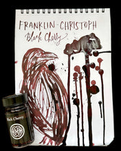 Load image into Gallery viewer, Franklin-Christoph Bottled Ink beside a raven sketch and ink splatters on a notepad.