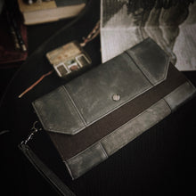 Load image into Gallery viewer, A Franklin-Christoph Fortis Clutch Envelope - Iron Brown &amp; Black sits next to a map and vintage camera.