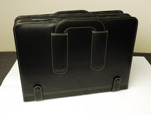 Load image into Gallery viewer, A black leather briefcase stands upright beside a Franklin-Christoph 80 Pen Case on a two-tone surface.