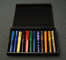 Load image into Gallery viewer, A Franklin-Christoph Covered Pen Tray displays twelve fountain pens, each in a slot, on a gray surface.