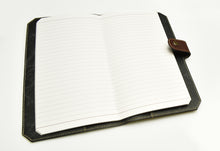 Load image into Gallery viewer, A Franklin-Christoph ETN - Cranberry executive travel notebook with a brown strap rests on a white surface.