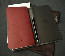 Load image into Gallery viewer, An open Franklin-Christoph ETN - Black Napa w/ Suit Grey and a black pen on gray fabric.