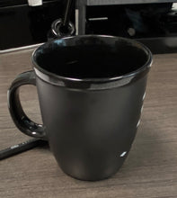 Load image into Gallery viewer, The Franklin-Christoph Coffee Mug 1, matte black with a handle, sits on wood next to a pen—sleek yet practical.