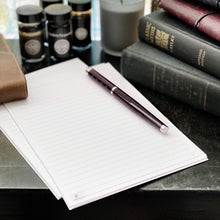 Load image into Gallery viewer, A pen rests on Franklin-Christoph Loose Leaf Sugar Paper beside books, ink bottles, a candle, and a leather pouch.