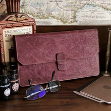 Load image into Gallery viewer, A brown New Penvelope 12 NWF by Franklin-Christoph sits on a desk with glasses, notebooks, and a vegan pen case.