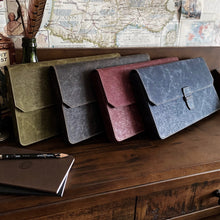 Load image into Gallery viewer, Four leather laptop sleeves in four colors on a desk with the Franklin-Christoph New Penvelope 12 NWF and a map.