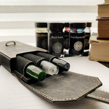 Load image into Gallery viewer, Franklin-Christoph New Penvelope 3 NWF with three ink vials, set against ink bottles and books on a desk.