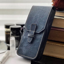 Load image into Gallery viewer, Franklin-Christoph New Penvelope 3 NWF: dark vegan pen case, removable slots, white stitch, upright by books and bottles.