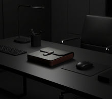 Load image into Gallery viewer, A closed leather briefcase on a black desk with a lamp and Franklin-Christoph New Penvelope 6 Black Merlot Leather.