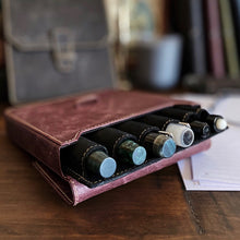 Load image into Gallery viewer, A Franklin-Christoph New Penvelope 6 NWF holds five pens open on a desk, with papers and a blurred bag behind.