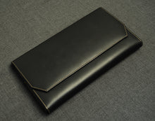 Load image into Gallery viewer, A black leather wallet and a Franklin-Christoph Penvelope Lucky 13 case with tan stitching sit on a gray textured surface.