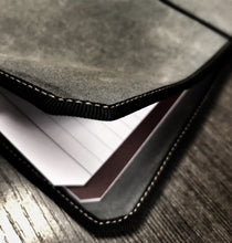 Load image into Gallery viewer, Close-up of a Vagabond Notebook covered in Franklin-Christoph Canvas, with lined paper, on a wooden surface.