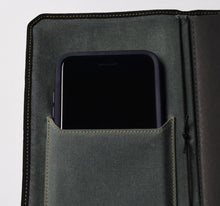 Load image into Gallery viewer, A smartphone in a gray canvas pocket inside a Vagabond Notebook Cover by Franklin-Christoph, with gold stitching.