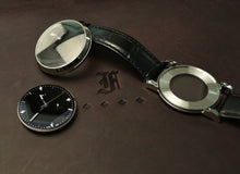 Load image into Gallery viewer, Franklin-Christoph IWO Timepiece disassembled on brown leather, showcasing face, case, parts, and stylized F logo.