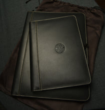 Load image into Gallery viewer, Two Franklin-Christoph Zippered Padfolios in black leather, stacked on a pouch atop dark fabric.